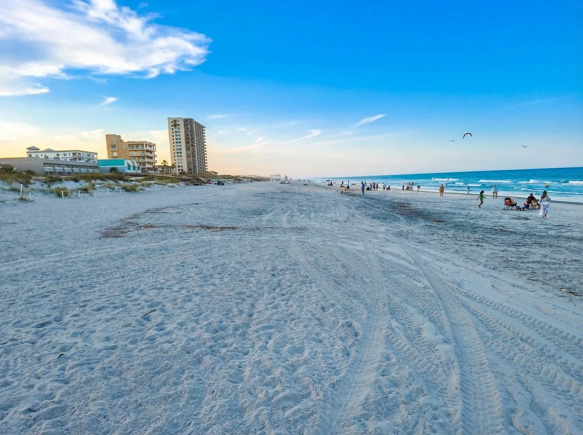 Jacksonville Beach looking north at dusk with wide open sand and buildings on the horizon